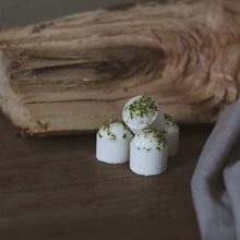 Load image into Gallery viewer, Petites boules de bain effervescentes blanches à points verts, devant un socle en bois