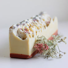Load image into Gallery viewer, Savon en pain crème, parsemé de fleurs séchées et herbes, avec éclats violets.