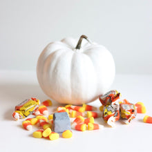 Load image into Gallery viewer, Masque solide au charbon : pain gris foncé près d’une citrouille blanche et bonbons.
